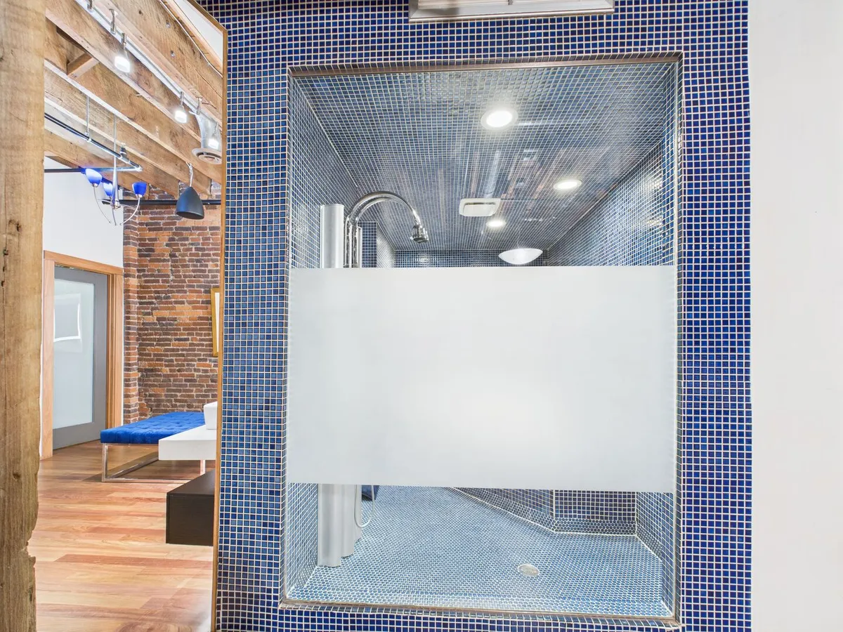 A modern bathroom featuring a glass shower enclosure, blue mosaic tiles, and sleek fixtures, offering a spa-like, rejuvenating shower experience.