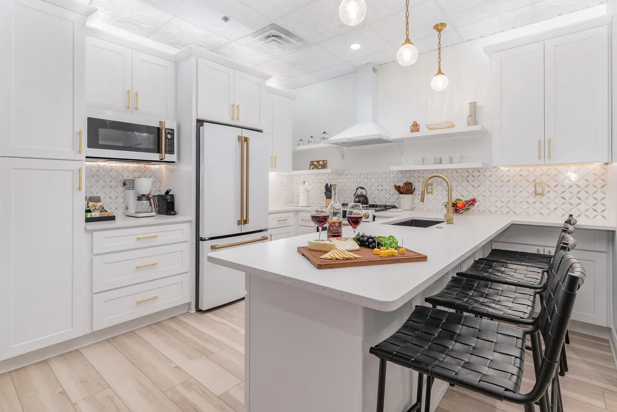 A modern kitchen island adorned with a charcuterie board, gold-accented cabinetry, pendant lighting, and state-of-the-art appliances. The arrangement encourages socializing during meal prep and creates a stylish, functional environment.