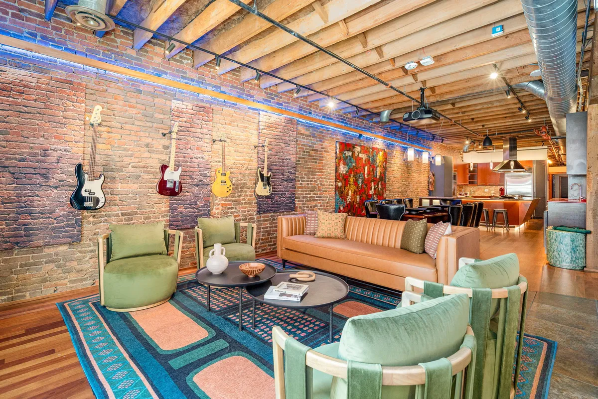 The hero image showcases a stylish living area with colorful guitars mounted on the wall, vibrant artwork, a modern seating arrangement, and a decorative rug, creating a lively and inviting atmosphere perfect for music lovers and groups.
