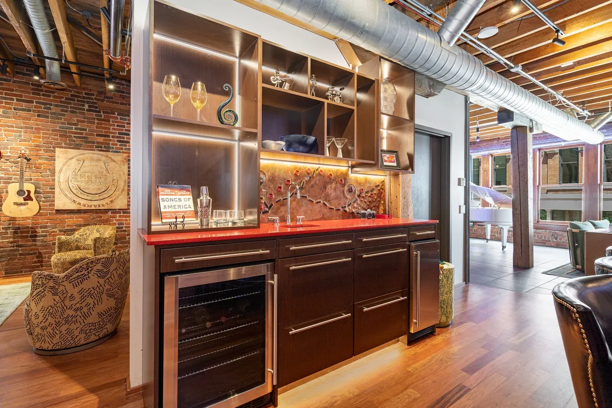 A sophisticated bar area featuring decorative glasses and a bold red countertop, creating an energetic spot for mixing drinks and socializing. The design exudes vibrancy and sets the stage for cocktail hours and lively evenings.